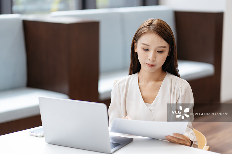 一位亚洲女性企业家在现代办公室处理商业文件图片素材