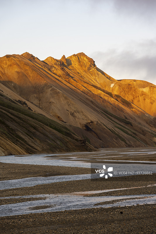 瑞奥利特山脉和约库尔吉尔斯克维斯尔河，兰德曼纳劳卡尔的风景，日落时分的戏剧性火山景观，色彩斑斓的侵蚀地貌与山脉，兰德曼纳劳卡尔，菲亚尔拉巴克自然保护区，南部地区，冰岛，欧洲图片素材
