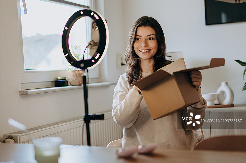 在线购物。微笑的年轻博主展示她的新购买。图片素材
