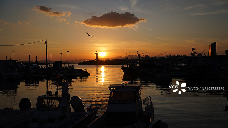 夕阳下，韩国港口停泊的帆船剪影与天空相映。图片素材