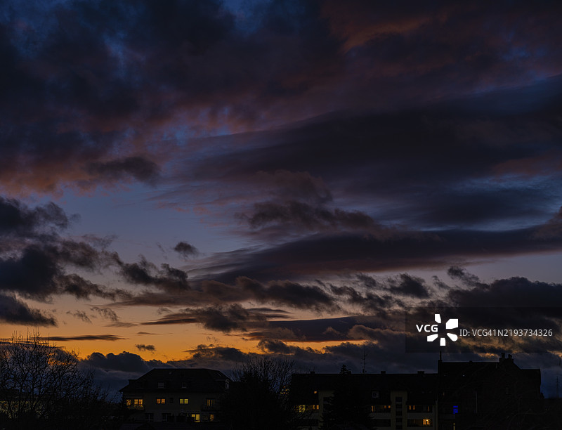 日落时分，天空中的云彩映衬着德国黑森州奥芬巴赫的住宅建筑图片素材