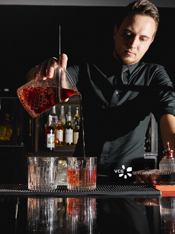 男调酒师在酒吧里将饮料倒入杯中图片素材