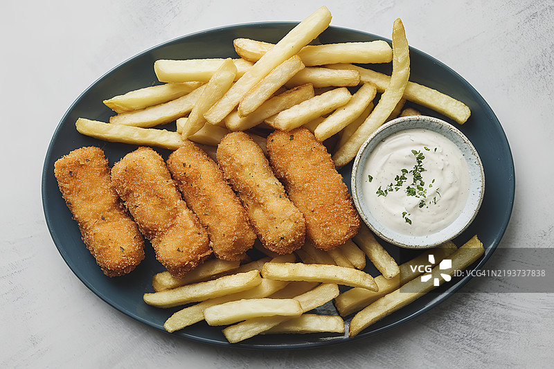 金黄色面包屑炸鱼条和酥脆的薯条放在白色盘子上图片素材