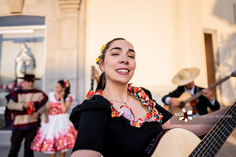 在智利圣地亚哥的民俗cueca活动中，一位华萨正在弹吉他。图片素材