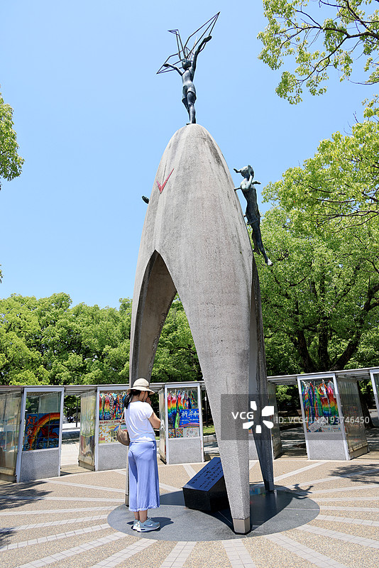 在日本广岛和平纪念公园的儿童和平纪念碑前祈祷的女性图片素材