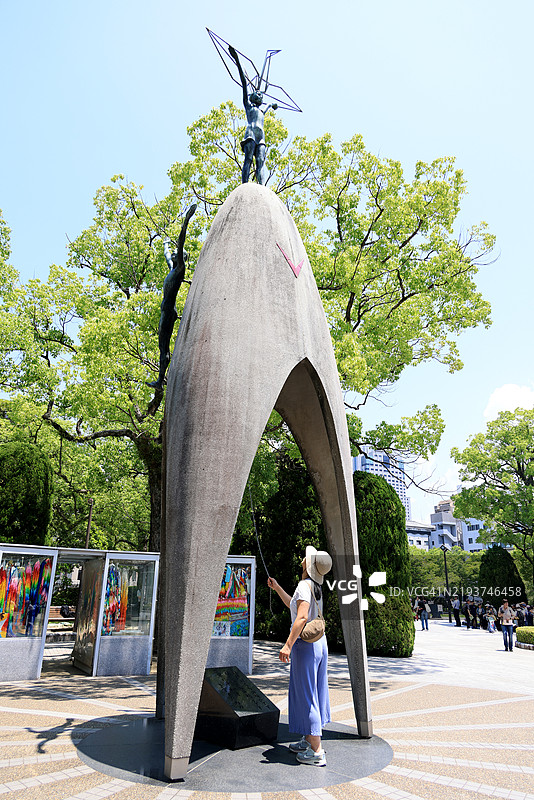 在日本广岛和平纪念公园的儿童和平纪念碑前敲响钟声的女性图片素材