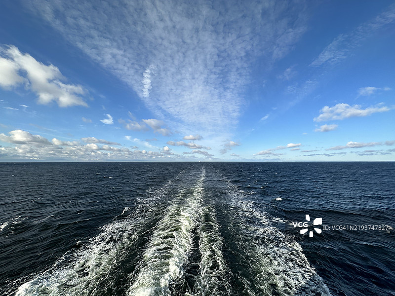 芬兰乌西马地区埃斯波附近的波罗的海上，渡轮在蓝天和云朵下留下的航迹图片素材