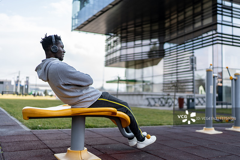 男子在公共公园做仰卧起坐图片素材