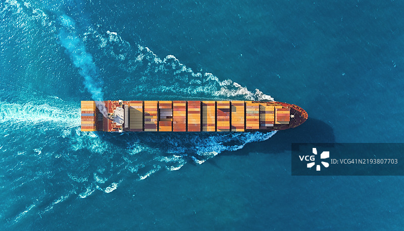 航拍视角的集装箱货船全速航行，伴随美丽的波浪图案，适用于商业物流、进出口、航运或货物运输。图片素材