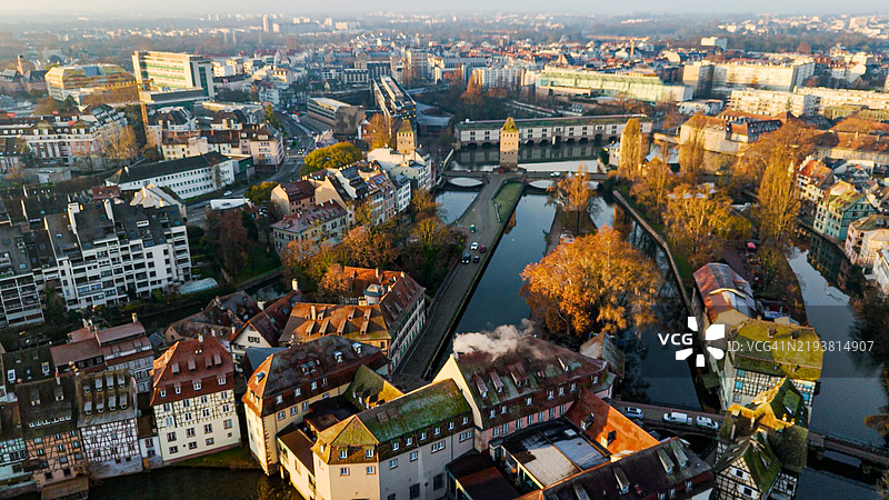 日出时分的斯特拉斯堡城市全景，展示了历史建筑和小法国区，突显了覆盖桥塔和沃邦水坝，展现了中世纪桥梁和标志性的斯特拉斯堡大教堂。图片素材
