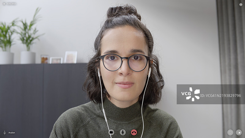 一位微笑的女性在视频会议中佩戴耳机的肖像图片素材