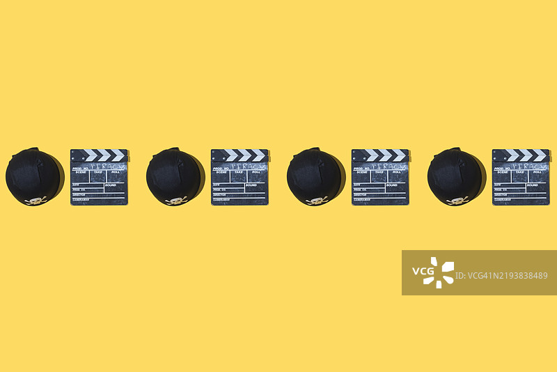 带有“盗版”字样的海盗帽和电影拍板的图案，排列在黄色背景上。海盗、盗贼、偷窃、版权、流媒体和法律。图片素材