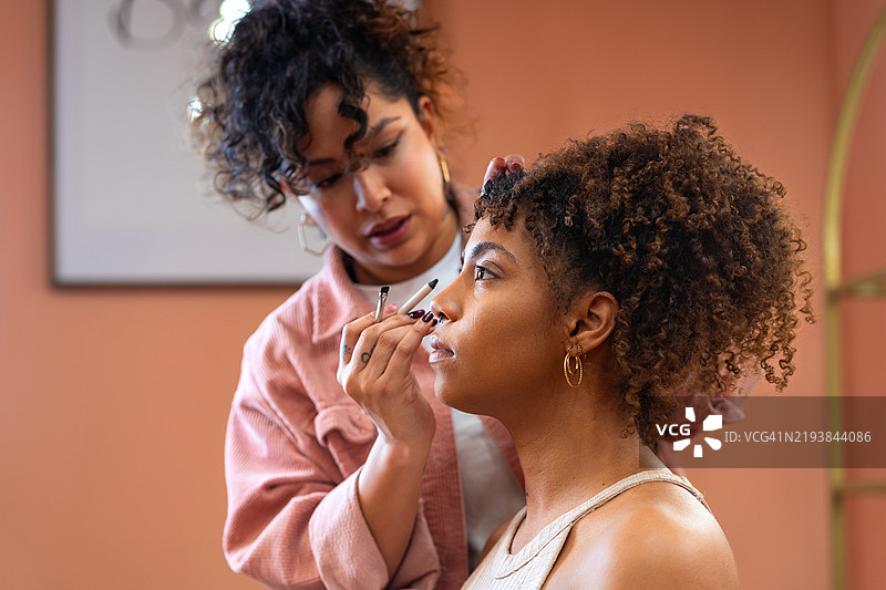 专业化妆师正在仔细为模特的脸部化妆，为她的拍摄或特殊活动做准备图片素材