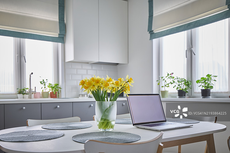 现代厨房空间，配有笔记本电脑和美丽的黄色花瓶展示图片素材