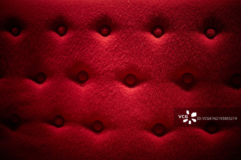 红色天鹅绒表面，带有按钮绗缝纹理，展现光滑设计图片素材