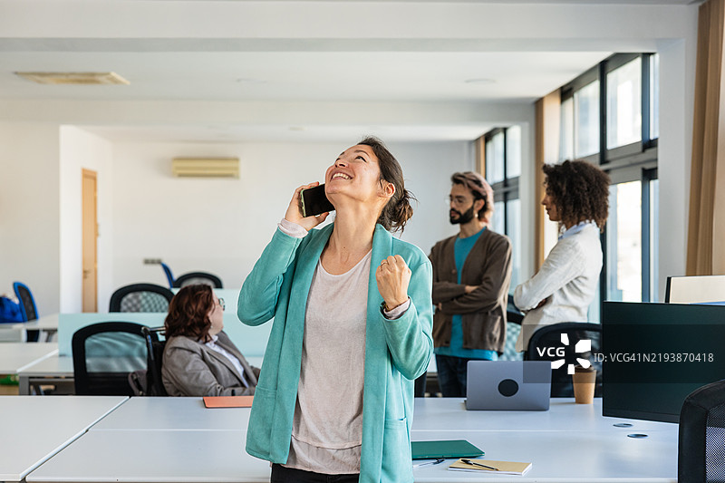 兴奋的女商人在办公室接到好消息的电话图片素材
