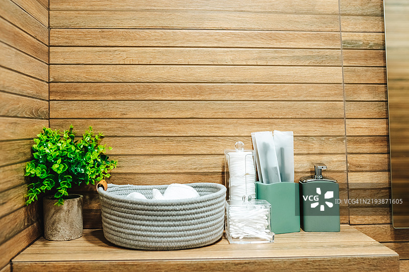 浴室用品整齐地摆放在木架上，装饰植物提升了氛围。图片素材