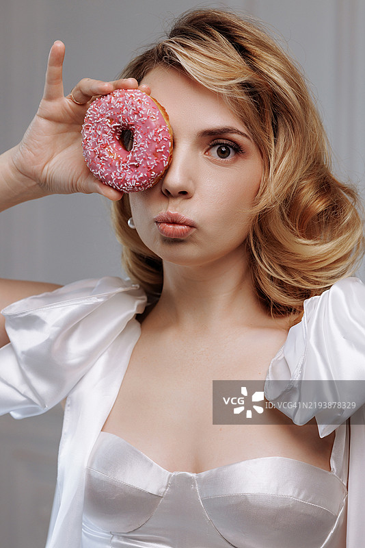 玩耍的女人手持粉色甜甜圈图片素材
