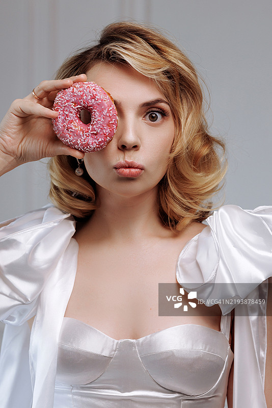 玩耍的女人手持粉色甜甜圈图片素材