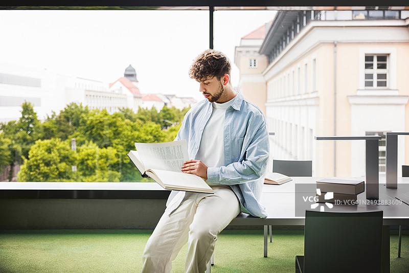 年轻男学生在图书馆窗边专心学习图片素材
