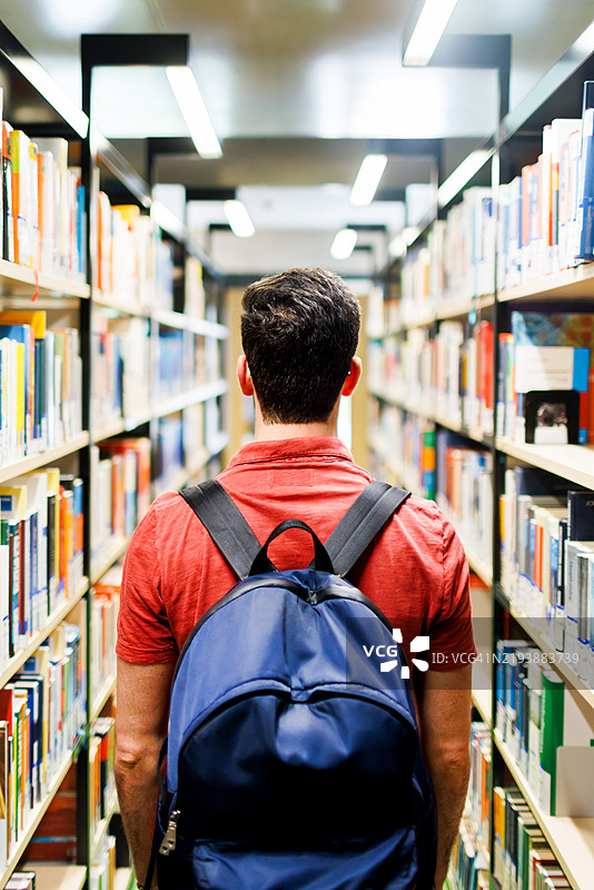 专注的学生在图书馆过道中寻找书籍图片素材
