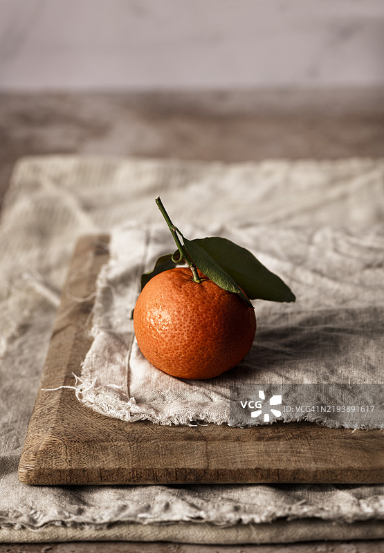 一颗新鲜有机的橘子，带着叶子，放在木板上图片素材