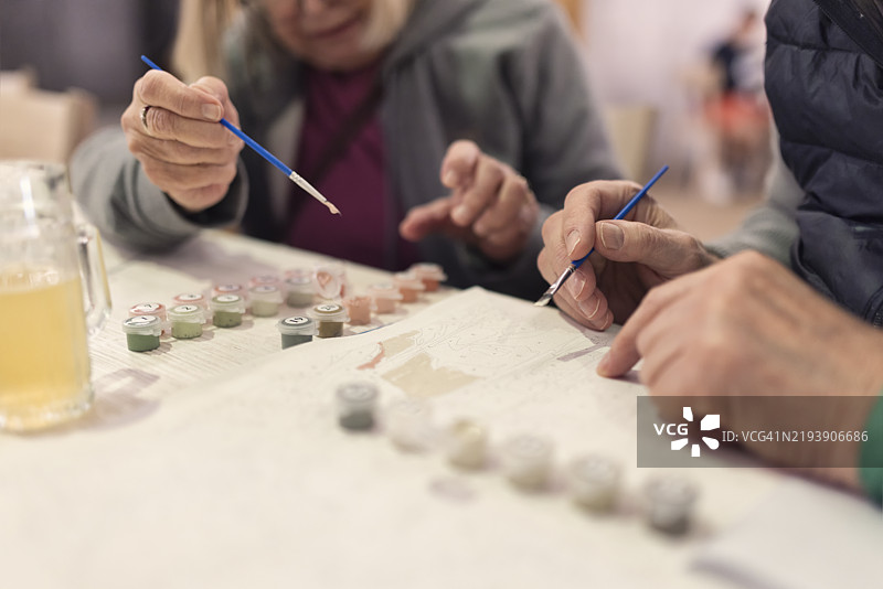 老年夫妇在桌子上进行数字画画。图片素材