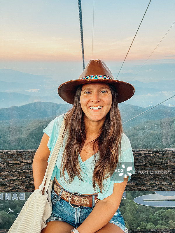 年轻女性享受在山脉上空的风景缆车之旅图片素材