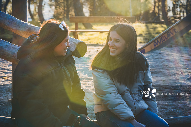 两个年轻女性在公园长椅上愉快地交谈图片素材