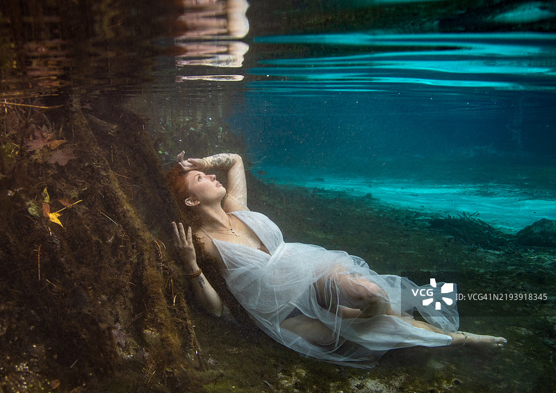 美丽的红发女性穿着长裙坐在佛罗里达州的河床下水中图片素材