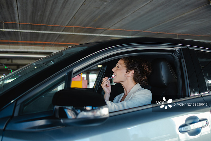 美丽的女人在车里涂口红图片素材