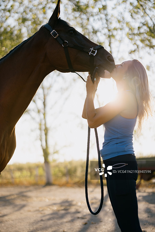 女人在户外日落时与棕色马分享时刻图片素材