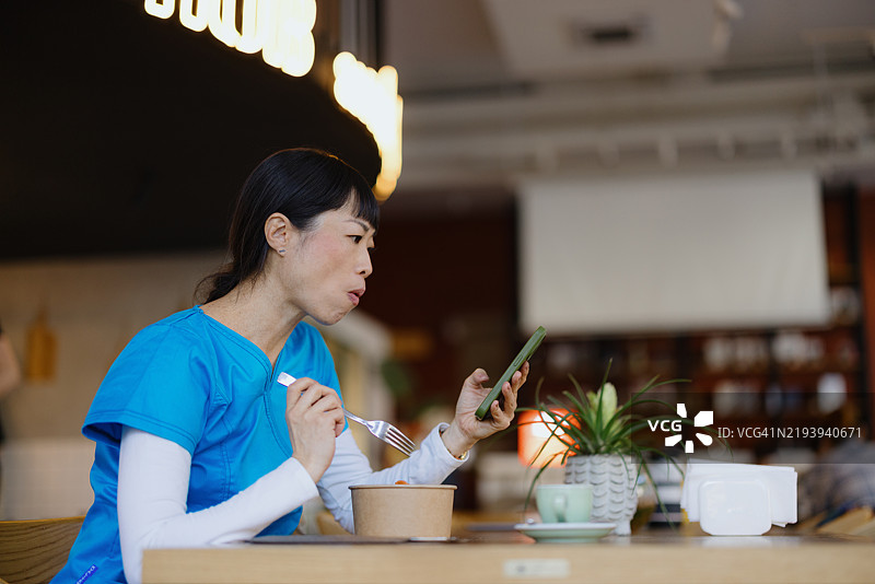 医疗工作者在用餐时浏览手机图片素材