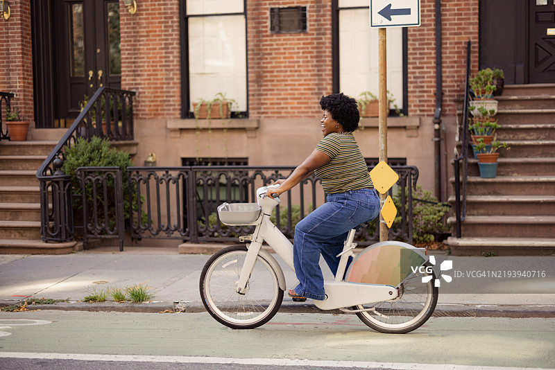 城市生活方式描绘：年轻女性骑公共租赁自行车图片素材