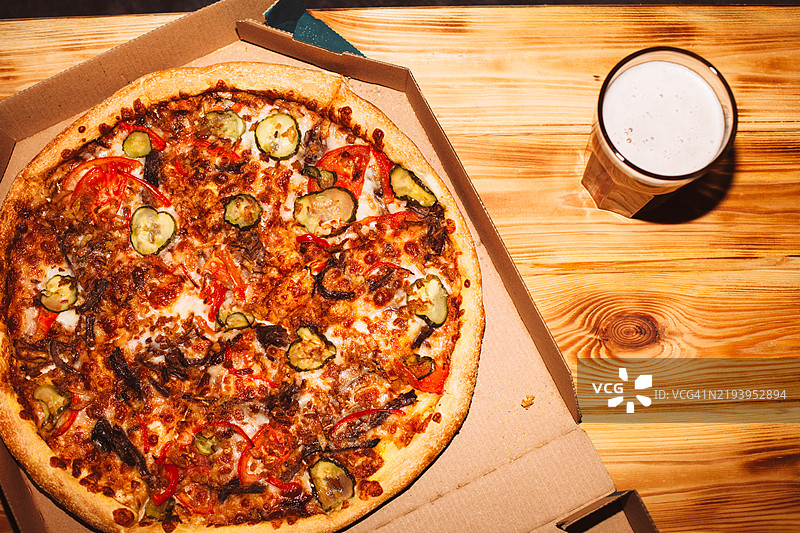 木桌上的比萨和一杯手工啤酒图片素材