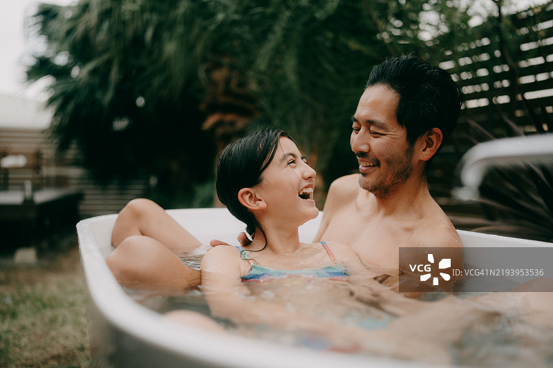 快乐的小女孩和她的父亲在后院的浴缸里玩耍图片素材