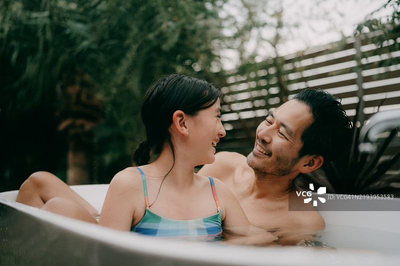快乐的小女孩和她的父亲在后院的浴缸里玩耍图片素材