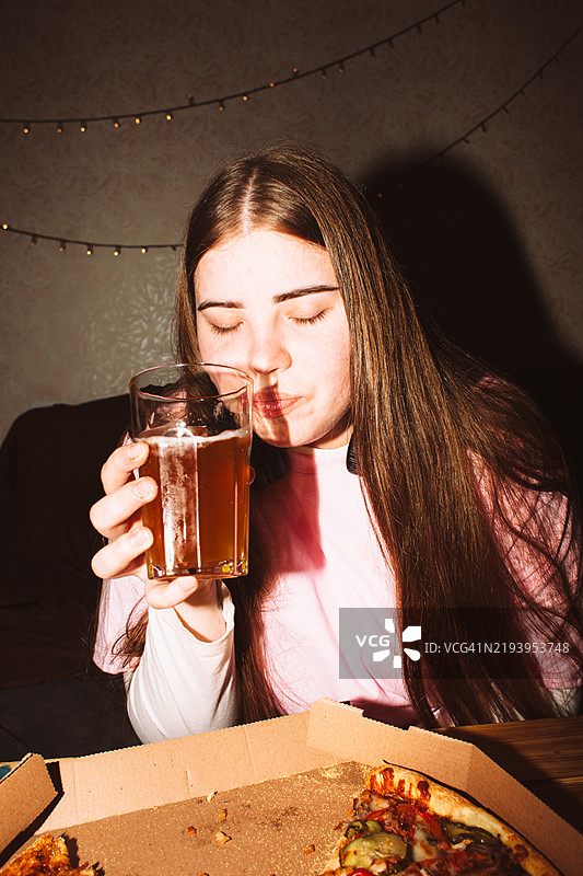 美丽的年轻女性在家派对上喝手工啤酒和吃披萨图片素材