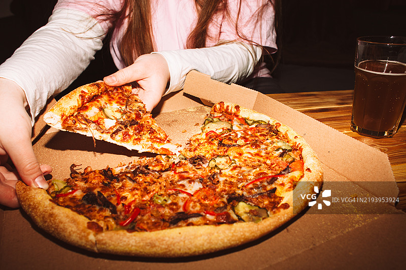 年轻女性在家庭聚会上拿一片披萨图片素材