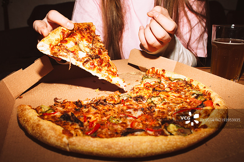 年轻女性在家庭聚会上拿一片披萨图片素材