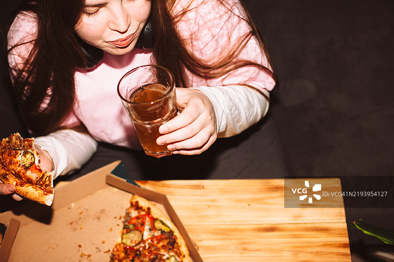年轻女性在家派对上吃披萨喝手工啤酒图片素材