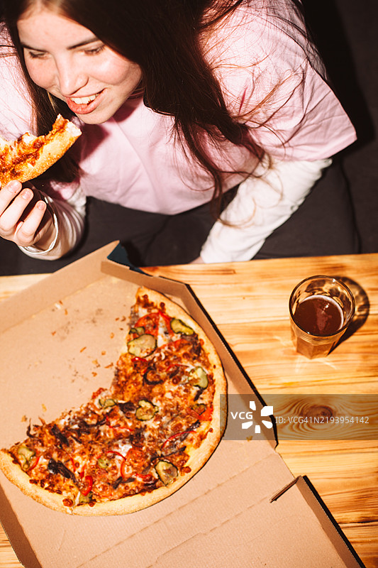 快乐的年轻女性在家派对上吃披萨图片素材