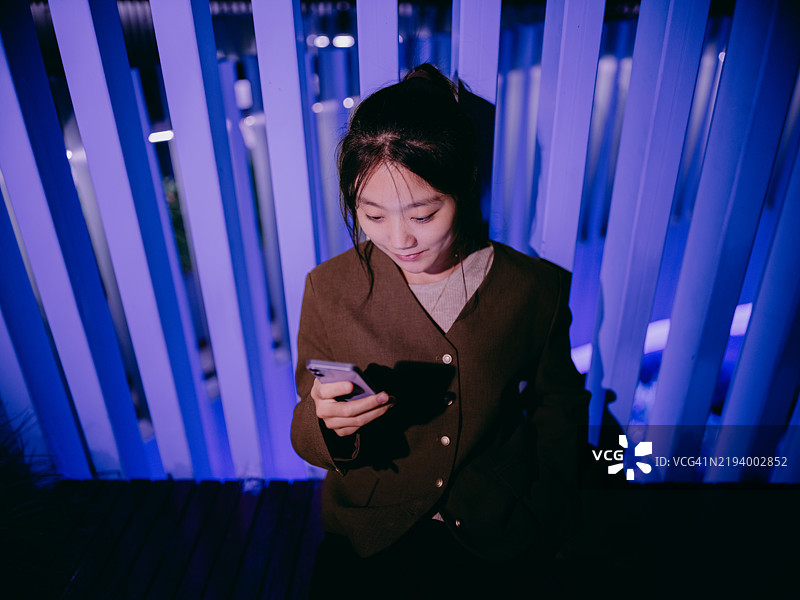 亚洲女商人在城市的发光人行天桥上使用智能手机图片素材