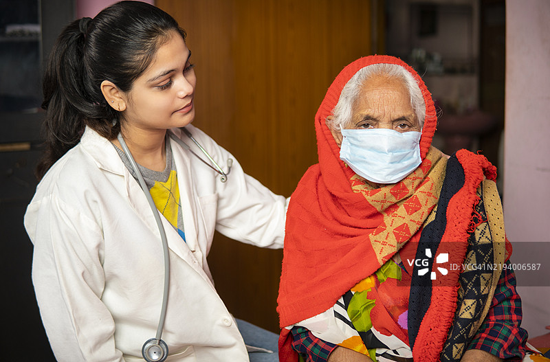 印度女性医生在家中安慰并给予老年女性患者心理支持。图片素材