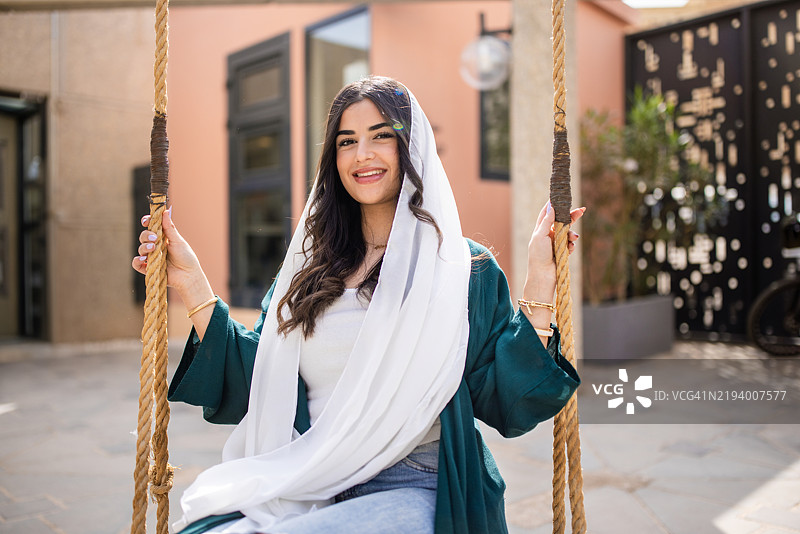 年轻的中东女性坐在秋千上图片素材