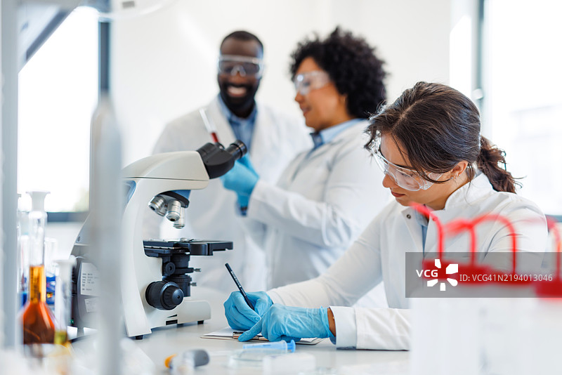 科学家在现代实验室中使用显微镜进行研究图片素材