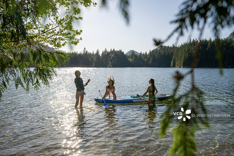母亲和女儿们在山湖上享受立式划水板活动图片素材