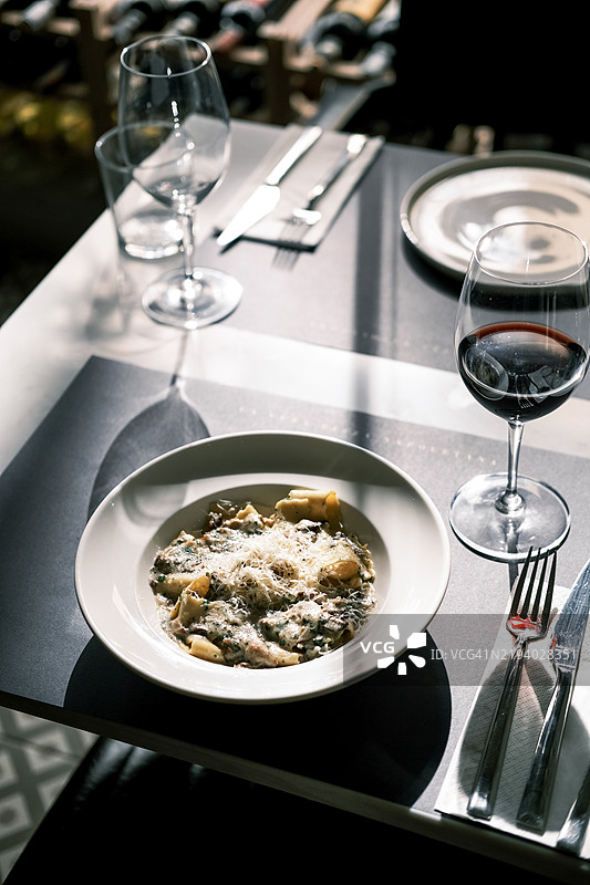 松露蘑菇宽面条配帕尔马干酪，搭配红酒，优雅的意大利餐厅，阳光明媚的桌面布置，精致的用餐氛围和奢华的美食体验图片素材