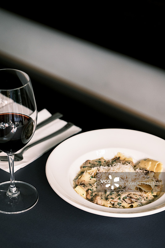 宽面条配牛肝菌和帕尔马干酪，经典意大利面食，搭配红酒，精致餐厅桌面布置，优雅的呈现方式图片素材