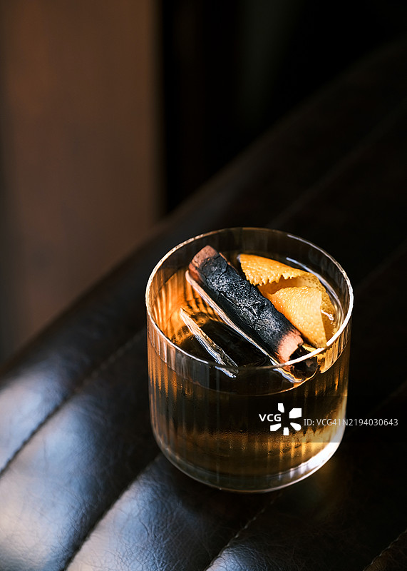 在质感玻璃杯中的波本马提尼，配以橙皮装饰，优雅地呈现在深色皮革表面，完美反映出奢华的意大利餐厅氛围。图片素材